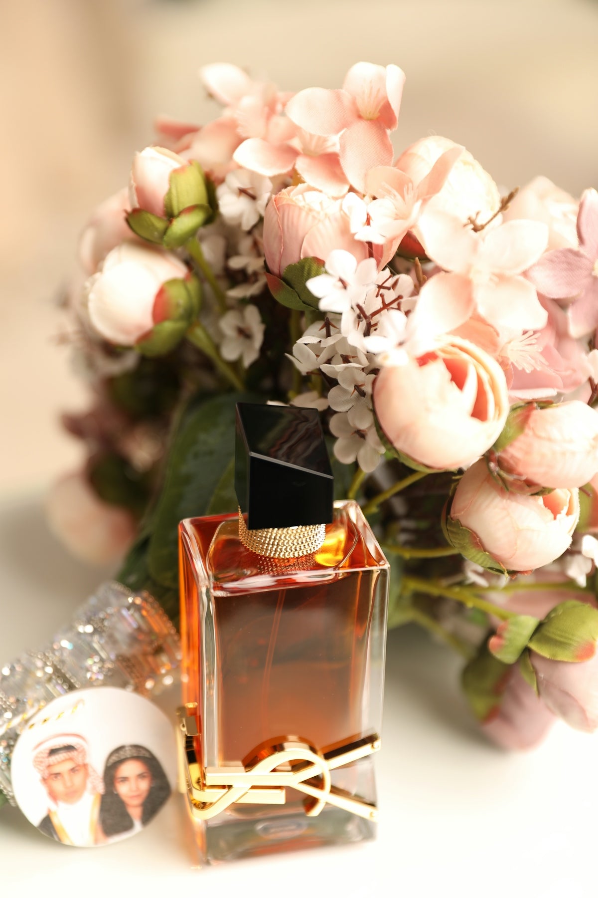 a bottle of perfume next to a bouquet of flowers